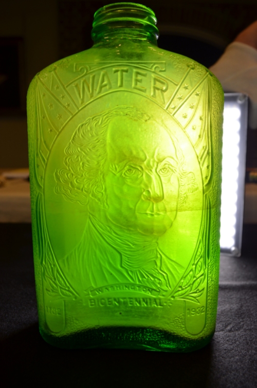 A green water bottle with a likeness of George Washington under the word "water." The bottle reads "Washington / Bicentennial" with the dates 1732 and 1932 on either side. It was made by the Hemingray Glass Company in Muncie, Indiana.
